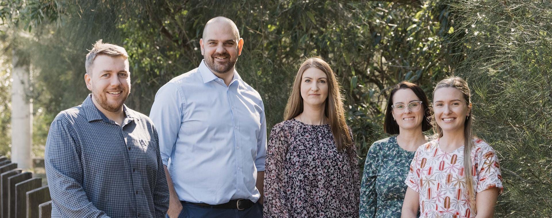 Five members of the Crest Accountants team standing together outdoors among native trees